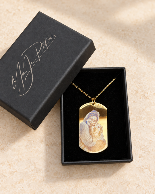 Digital gestaltete Studioansicht auf Basis der Originalaufnahme IMG_9651: goldfarbener Edelstahl-Foto-Dogtag an optionaler goldfarbener Kette in der optionalen großen MaJe-Geschenkschachtel; Hintergrund digital gestaltet