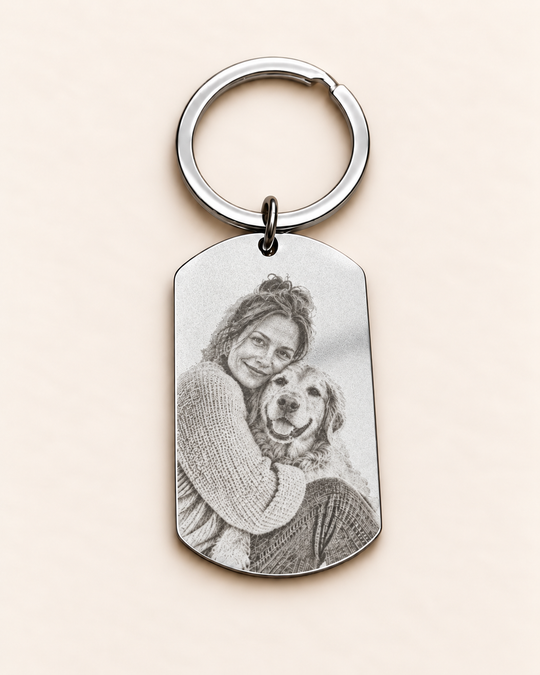 Silberfarbener Edelstahl-Dogtag ca. 49 × 28 mm mit passendem Schlüsselring und flacher Fotogravur von Frau und Hund. Digital gestaltetes Beispiel.
